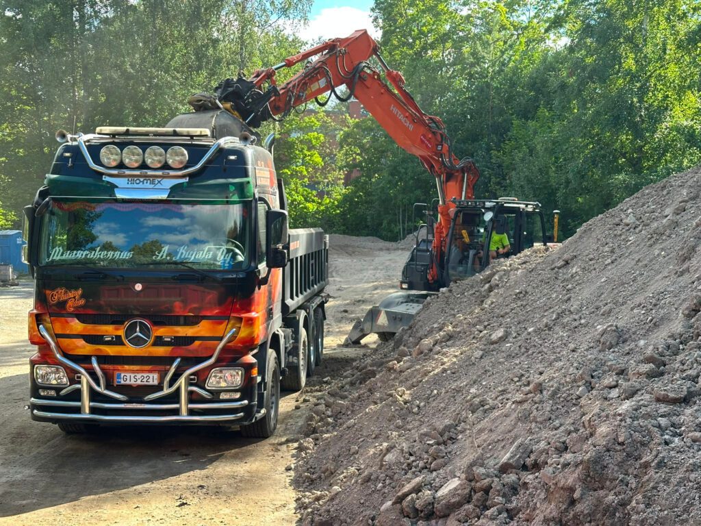 Kaivinkone lastaa Maanrakennus A. Kujala Oy:n kuorma-autoa työmaalla